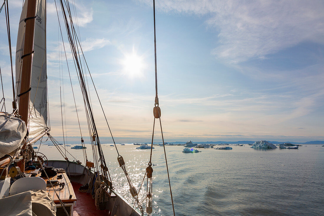 Ship sailing near melting icebergs on tranquil