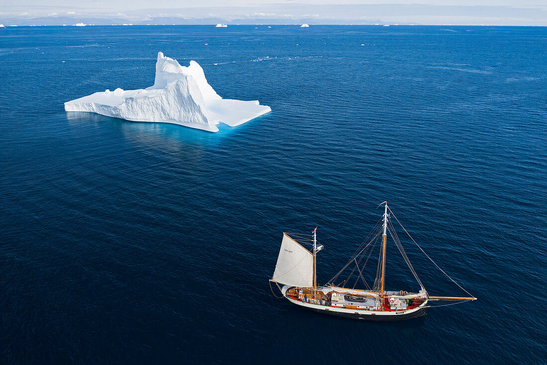 Ship sailing past majestic iceberg on blue