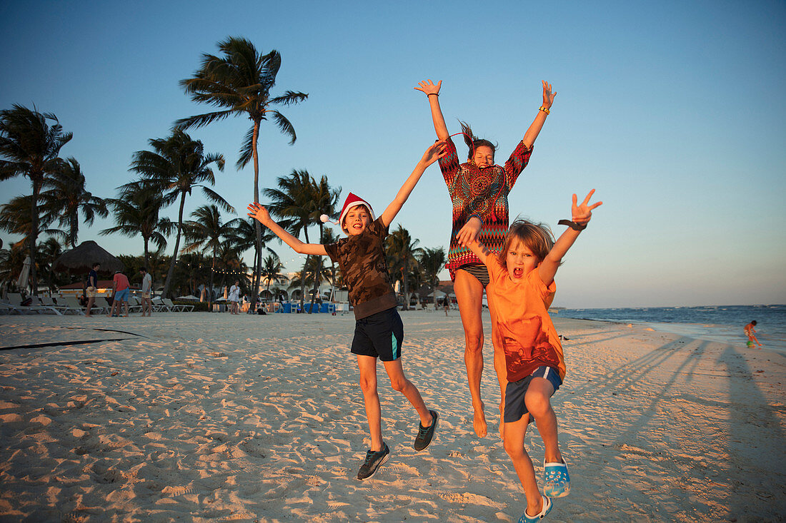 Portrait carefree family jumping on tropical beach