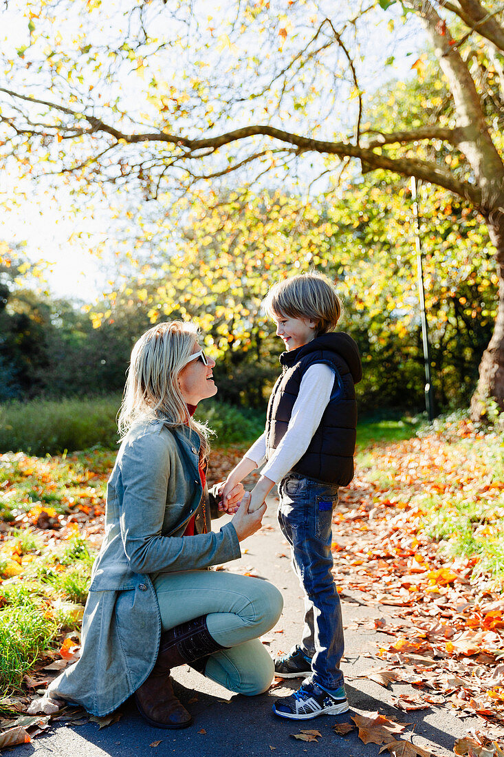 Mother and son holding hands and talking in autumn park