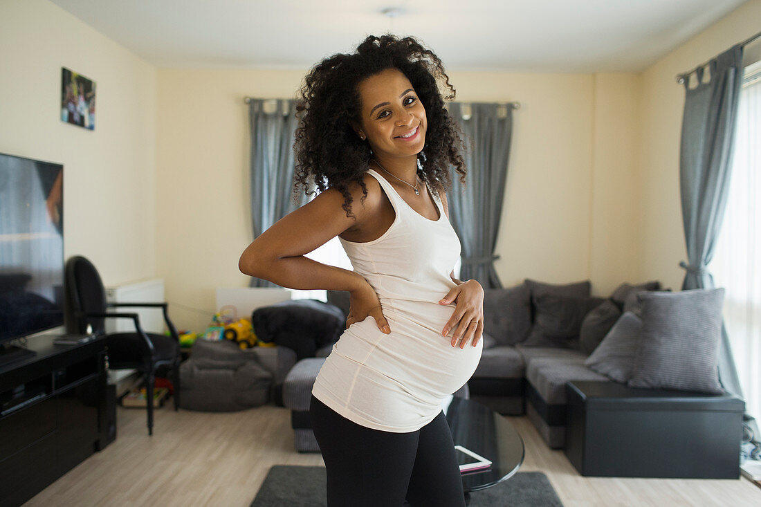 Portrait happy pregnant woman in living room