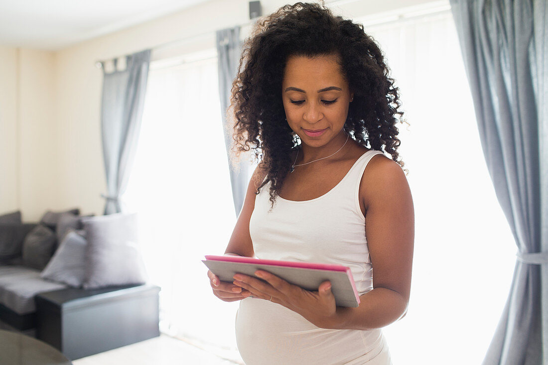 Young pregnant woman using digital tablet