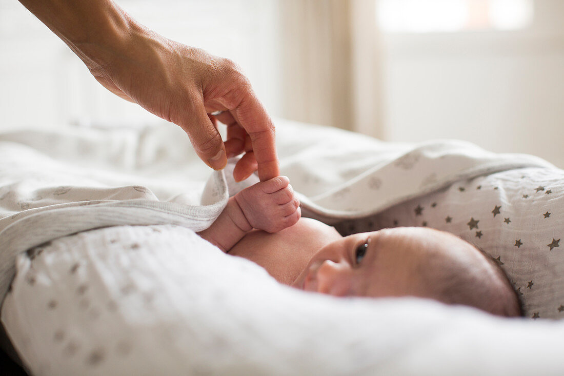 Mother holding hands with newborn baby boy