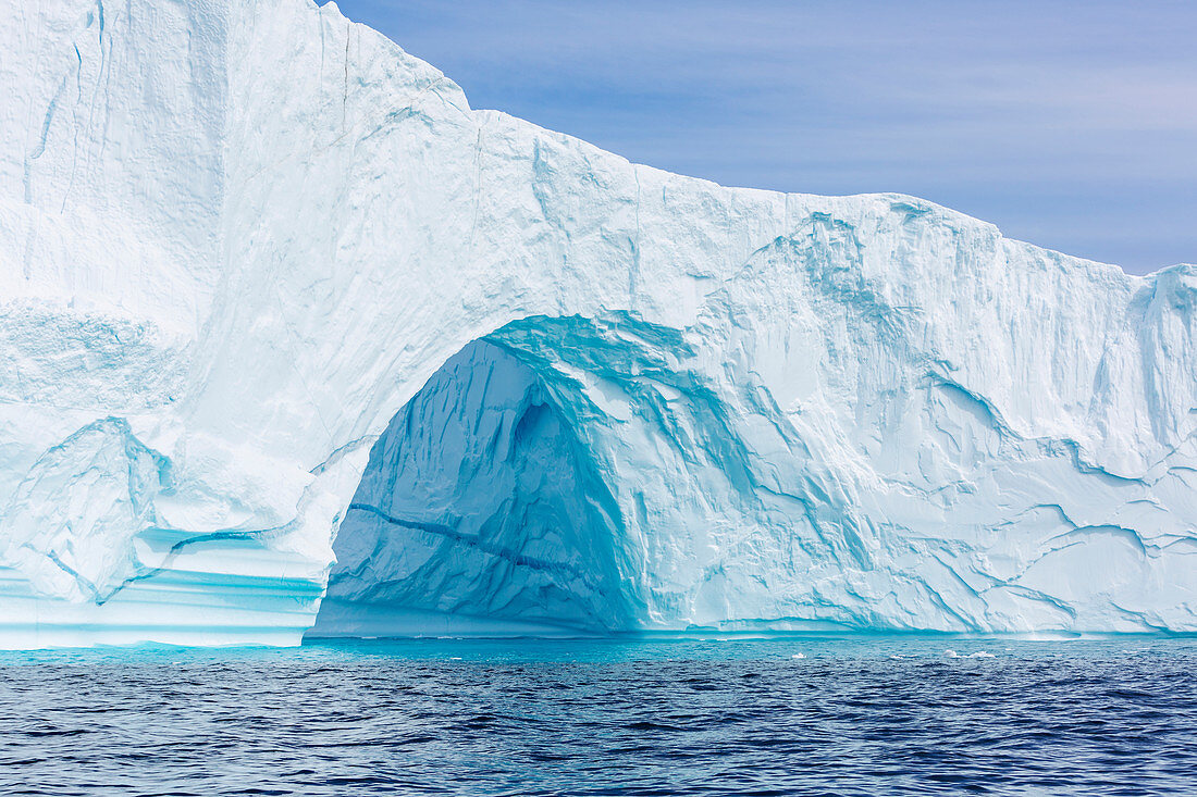 Majestic iceberg arch over blue ocean Greenland