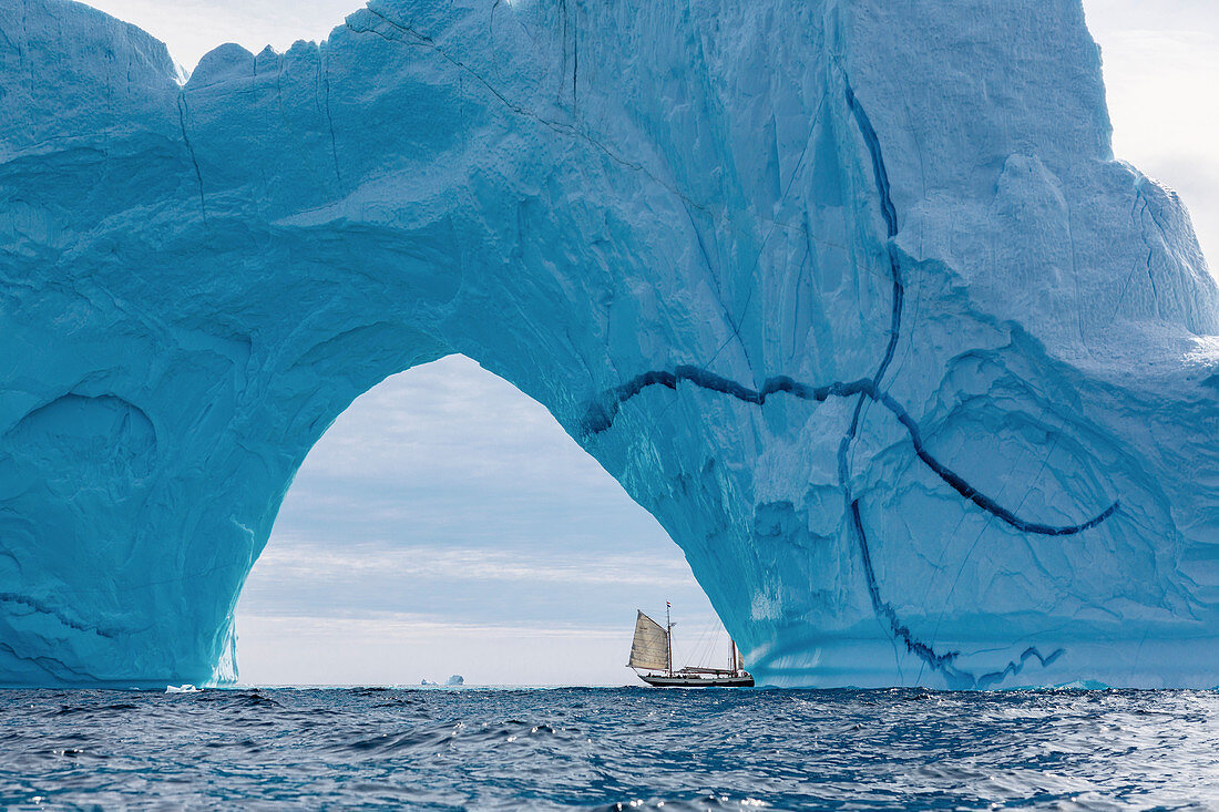 Sailboat under majestic iceberg arch