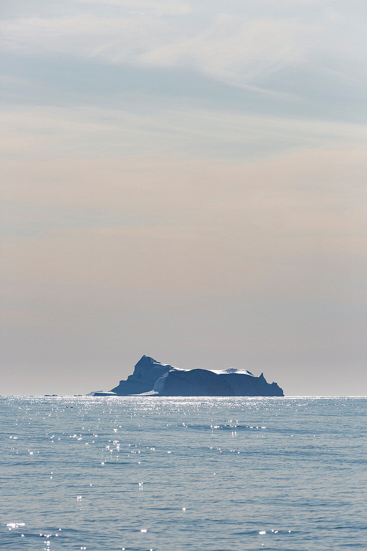 Iceberg in distance on tranquil Atlantic Ocean Greenland