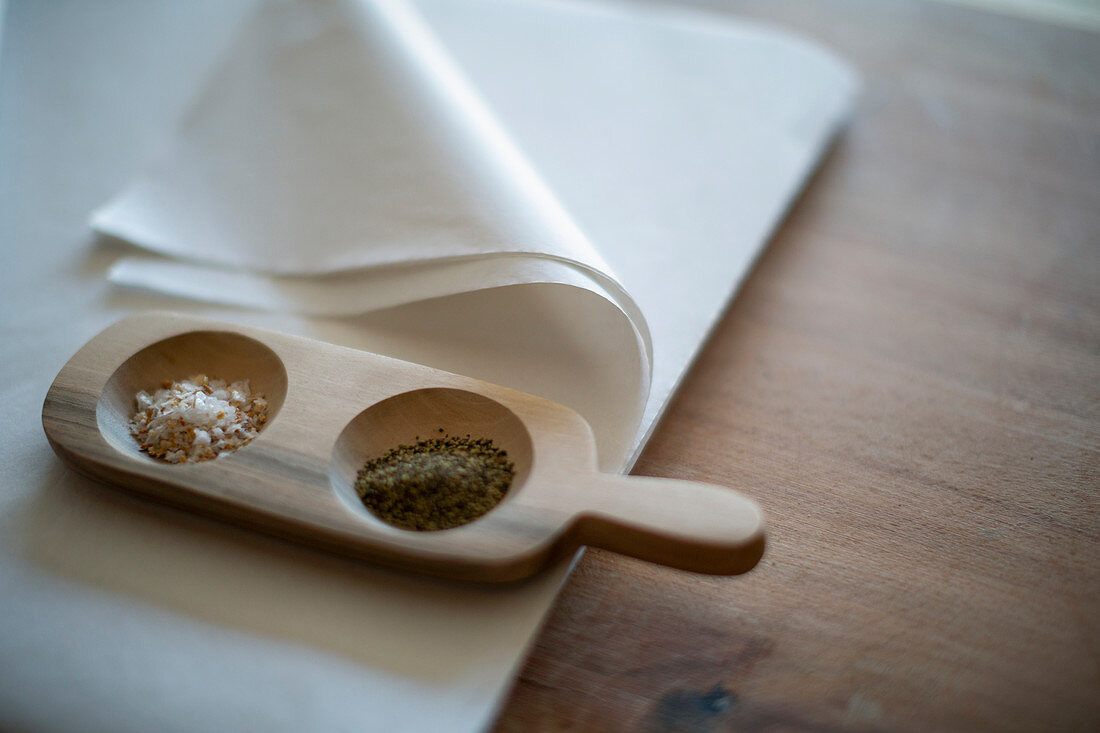 Gourmet salt and pepper in wooden tray on tissue paper