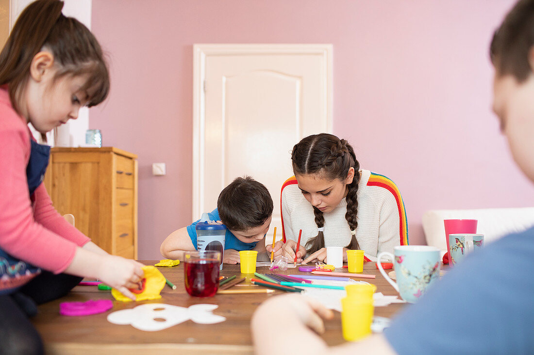 Brothers and sisters colouring at dining table