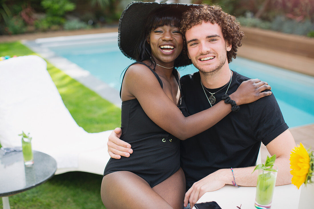 Portrait happy multiethnic couple relaxing at poolside