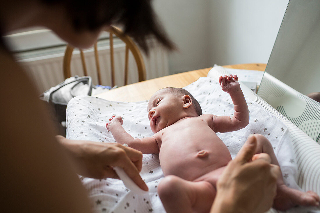 Mother changing diaper of newborn baby son