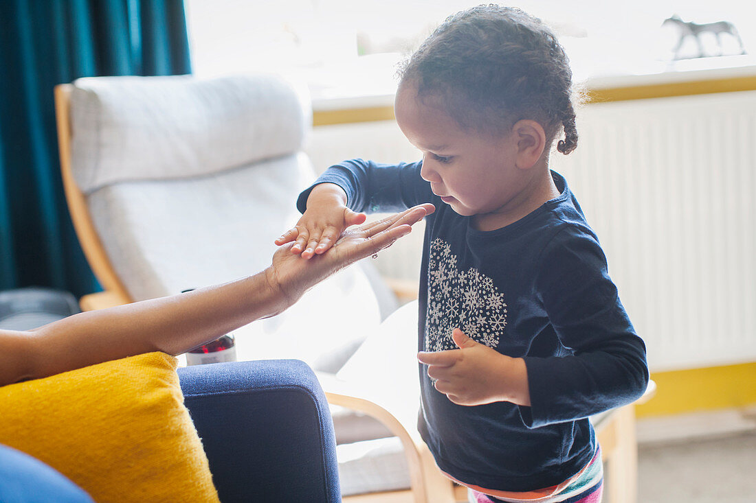 Curious girl touching hand of mother