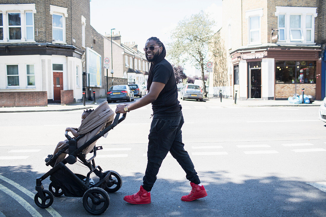 Father pushing toddler son in stroller on urban street