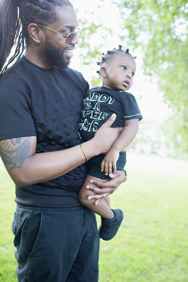 Father holding toddler son in park