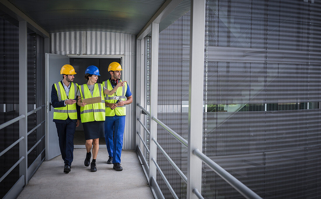Supervisors with clipboard walking on elevated walkway