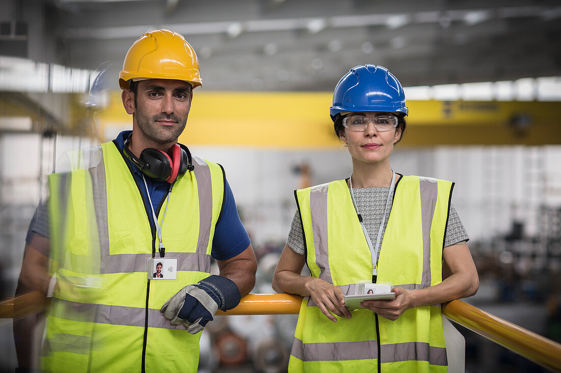 Supervisors with digital tablet on platform in factory