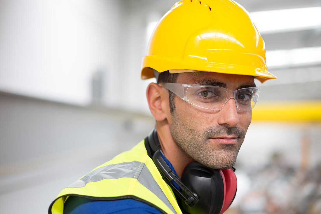 Male worker in protective eyewear and hard-hat in factory