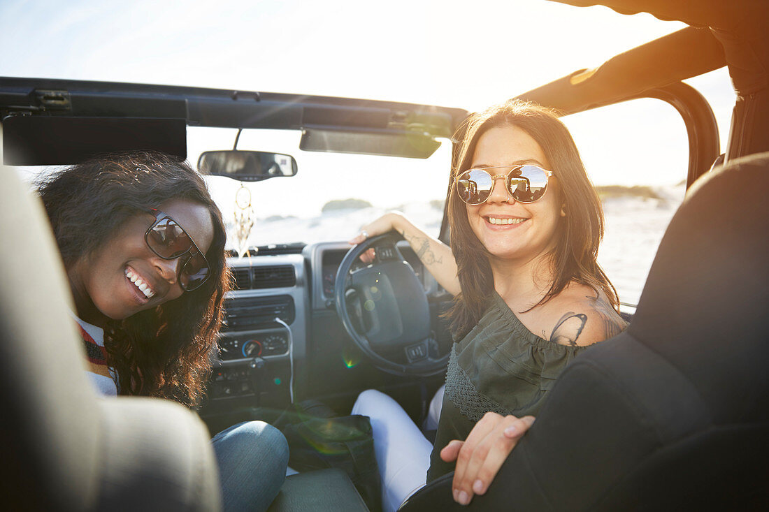 Smiling young women wearing sunglasses in sunny jeep