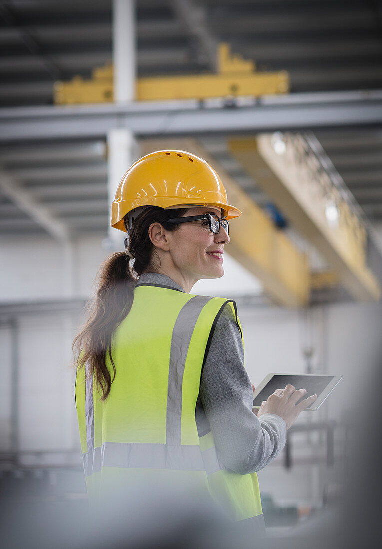 Confident female worker using digital tablet in factory
