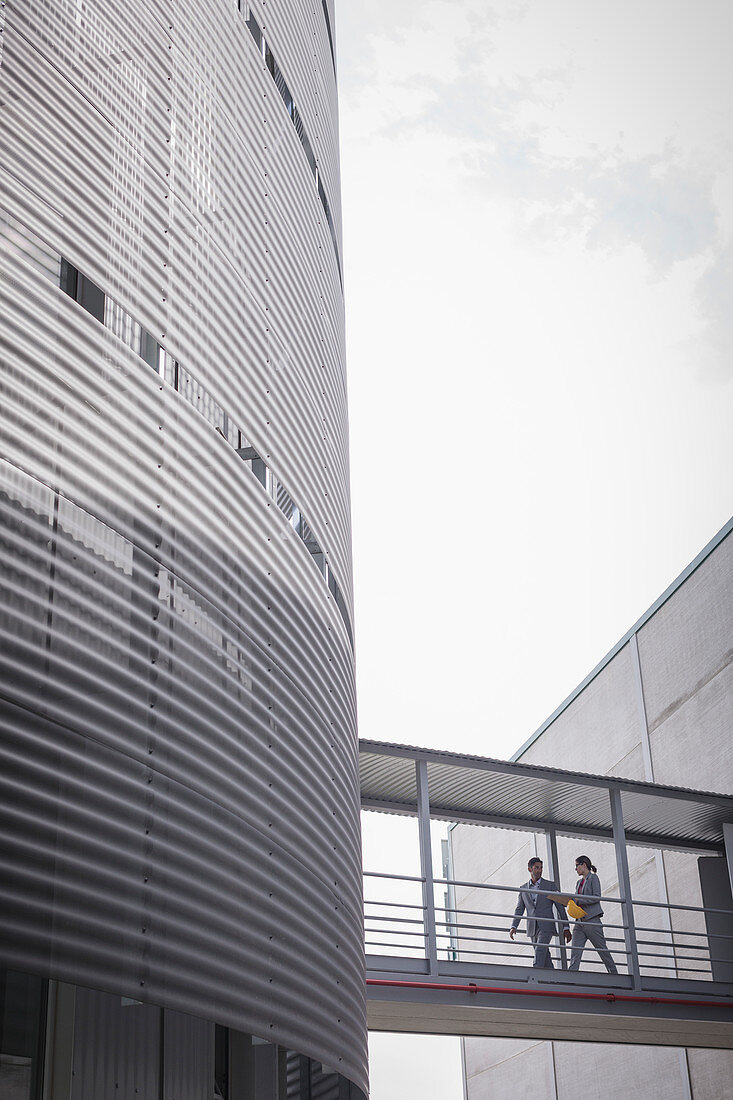 Supervisors walking on walkway between factory buildings