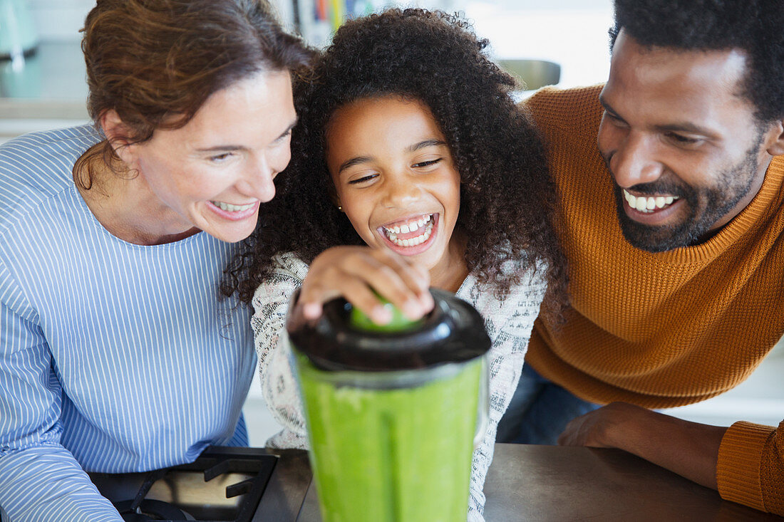 Laughing multi-ethnic family making healthy green smoothies