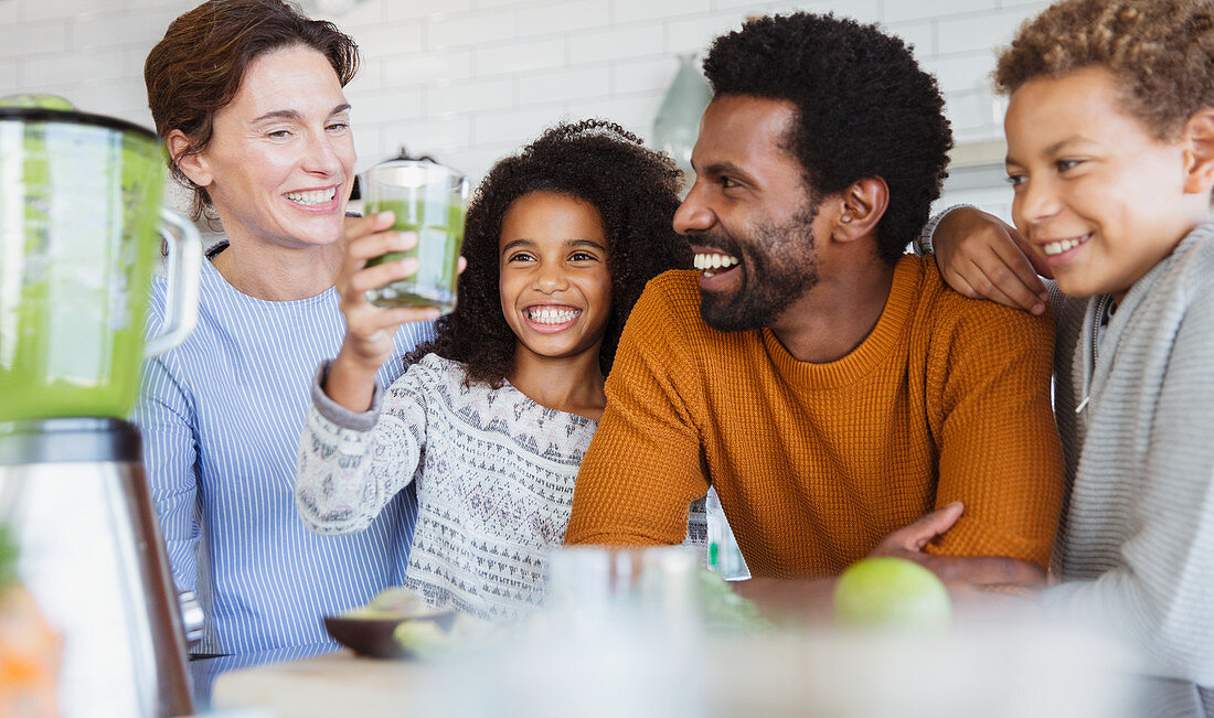 Multi-ethnic family drinking healthy green smoothie
