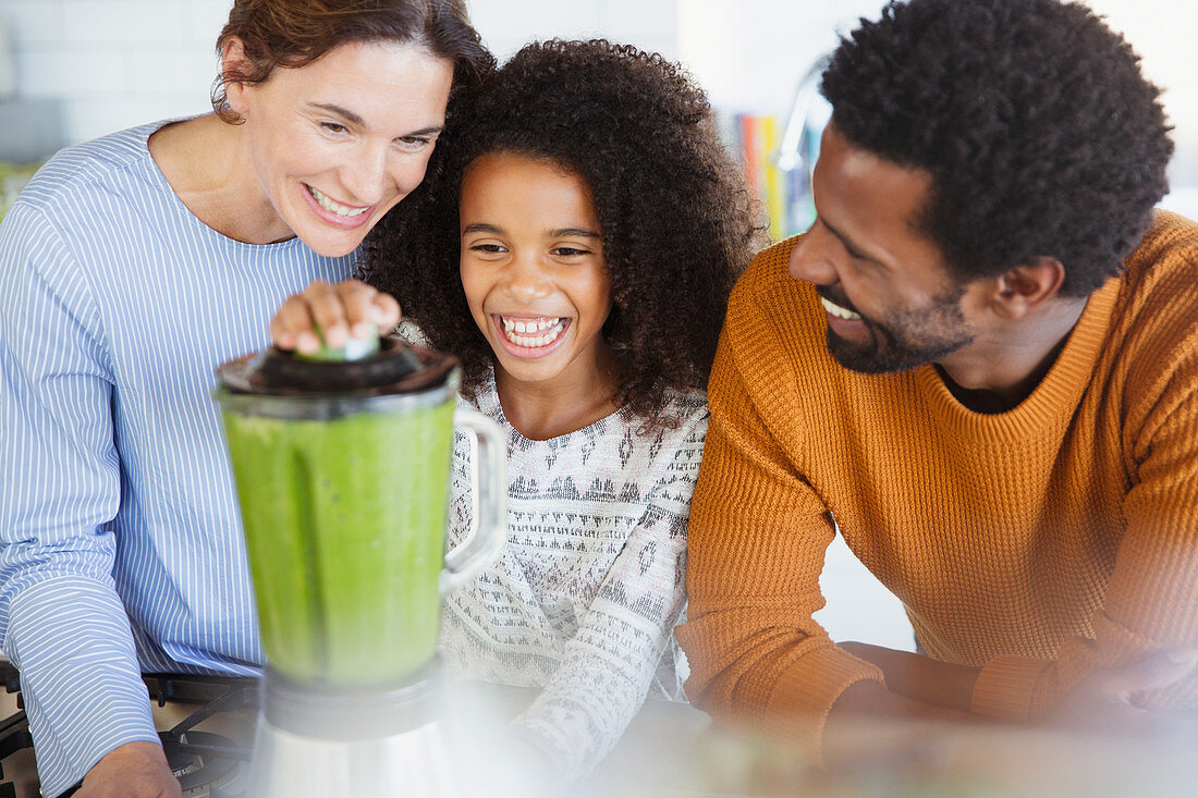 Multi-ethnic family making healthy green smoothie in blender