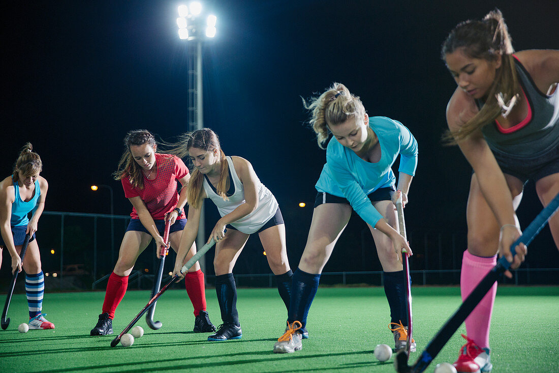 Female hockey players practicing sports drill on field