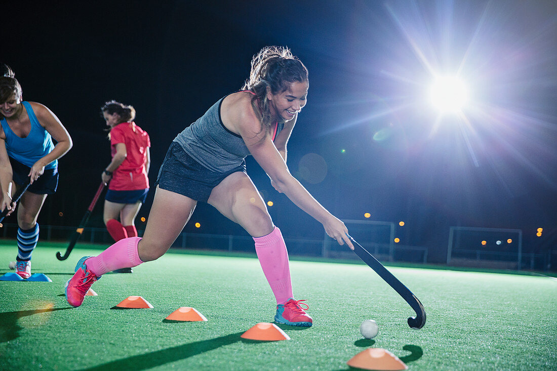 Female hockey player practicing sports drill on field