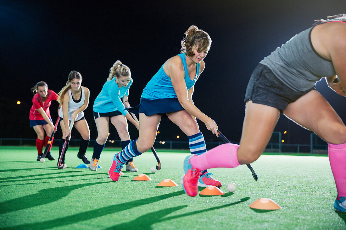 Female hockey players practicing sports drill on field