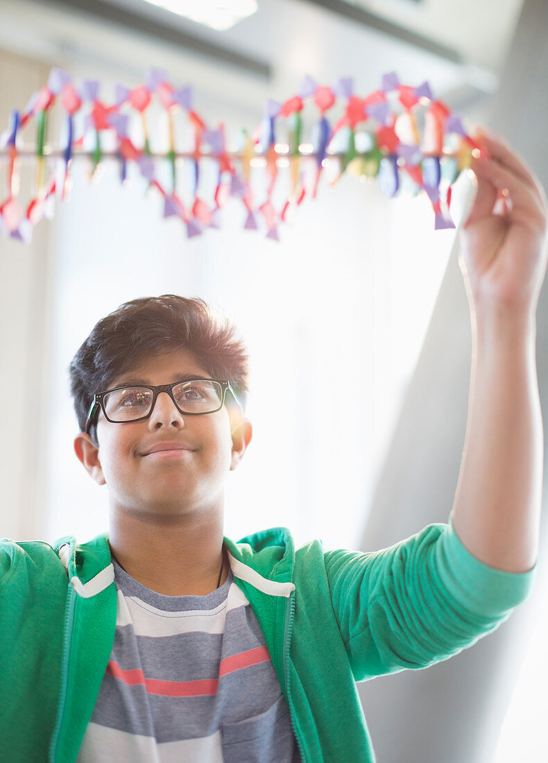 Boy student examining DNA model in classroom