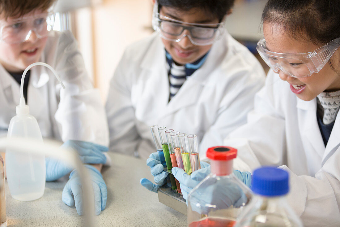Students examining liquids in test tube rack in classroom