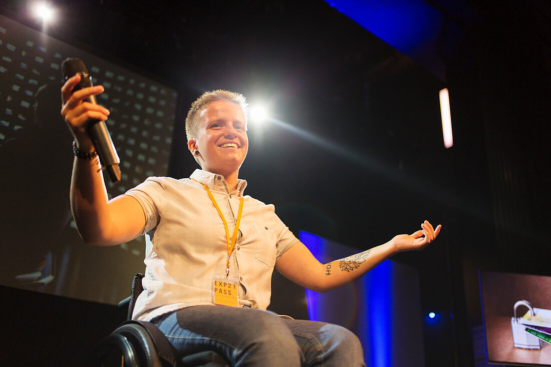 Confident female speaker in wheelchair on stage