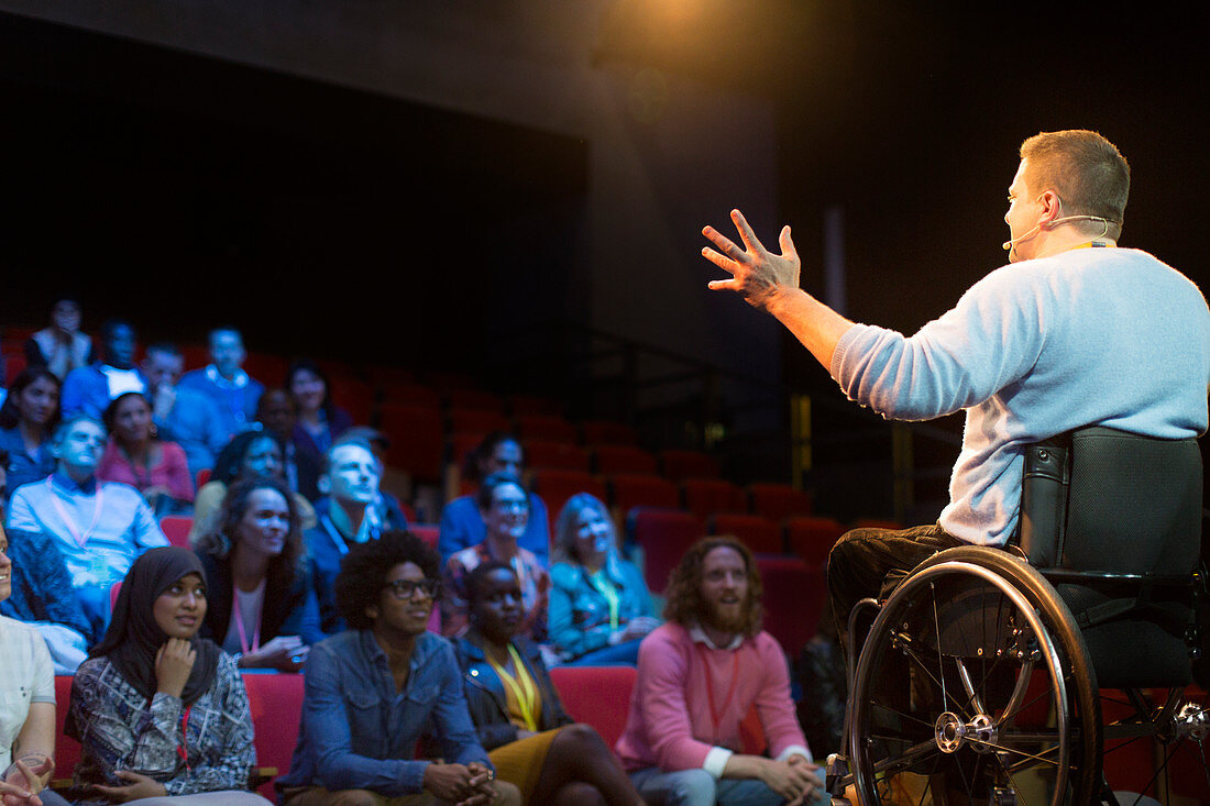 Speaker in wheelchair on stage talking to audience