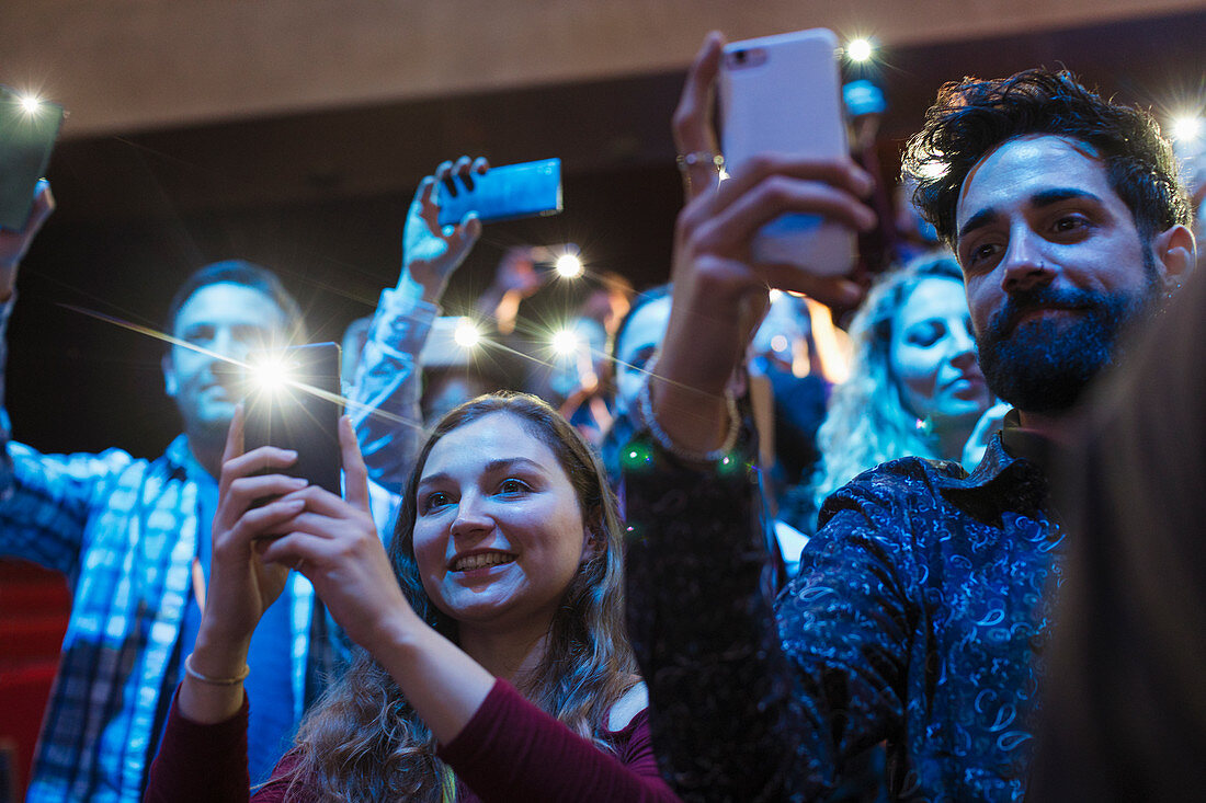 Smiling audience using smart phone flashlights