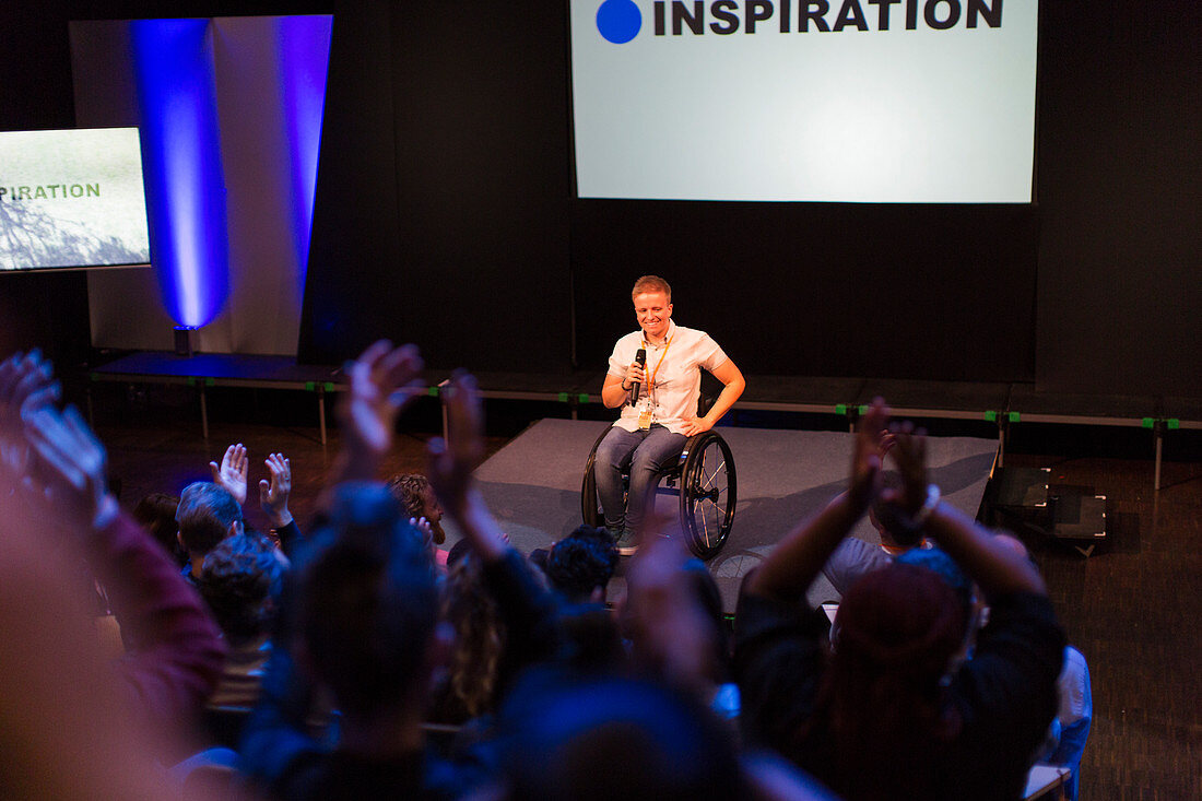 Female speaker in wheelchair on stage talking to audience
