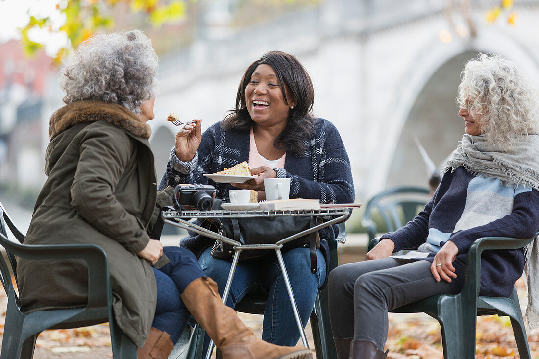 Laughing active senior women friends sharing dessert