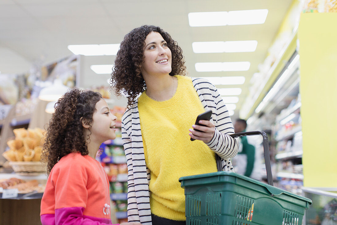 Mother and daughter with smart phone shopping in supermarket