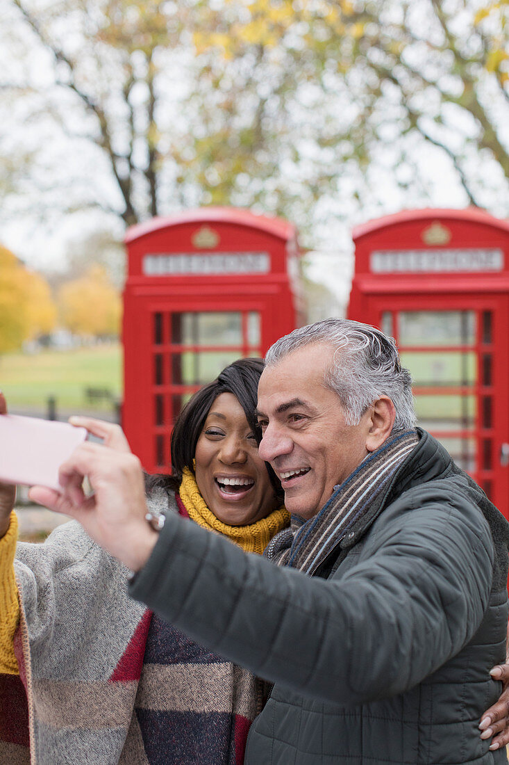 Couple taking selfie in front of red telephone booths