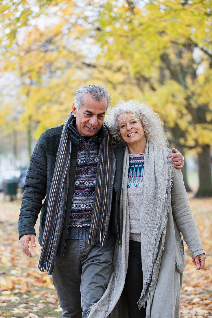 Smiling senior couple hugging and walking in autumn park