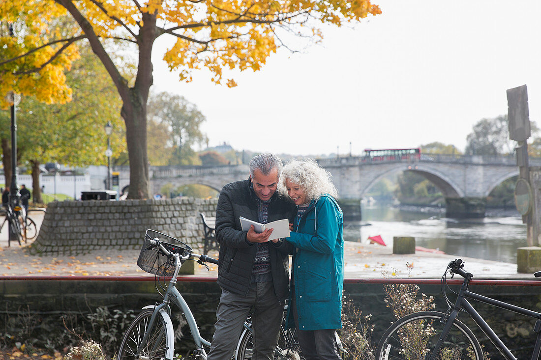 Senior couple with bicycles looking at guidebook