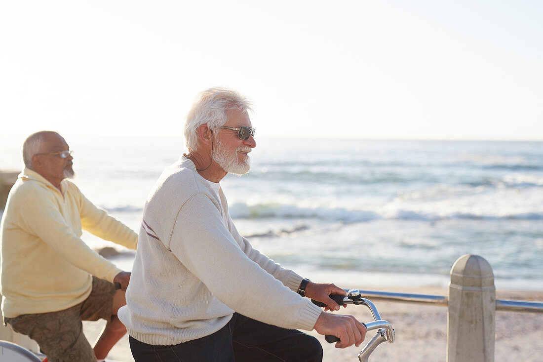 Active senior men bike riding, enjoying ocean view