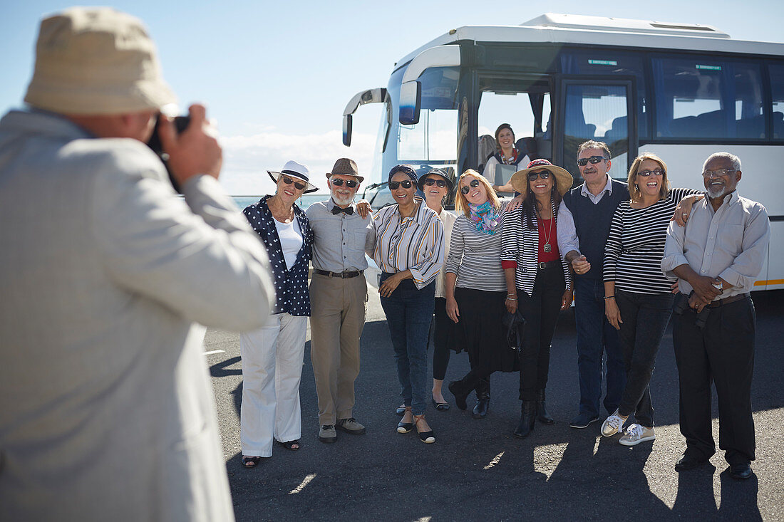 Senior tourist friends posing for photograph outside bus