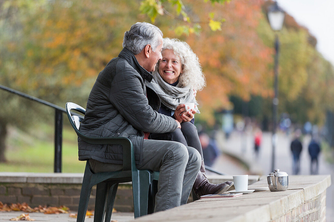 Affectionate active senior couple drinking tea in park