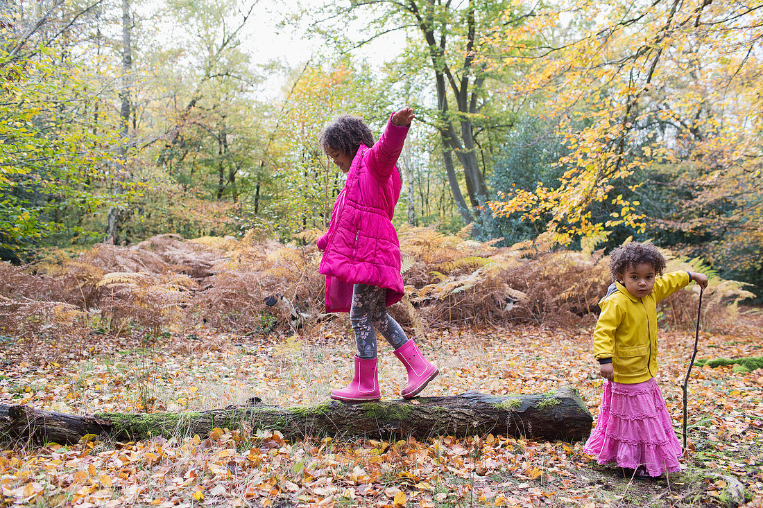 Girl walking on fallen log in autumn woods