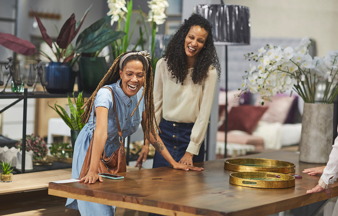 Happy women shopping for dining table in home decor shop