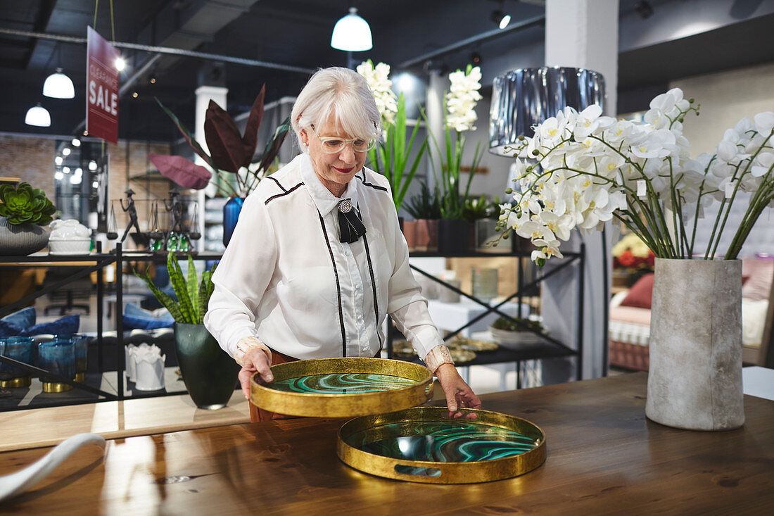 Senior woman looking at trays in home decor shop