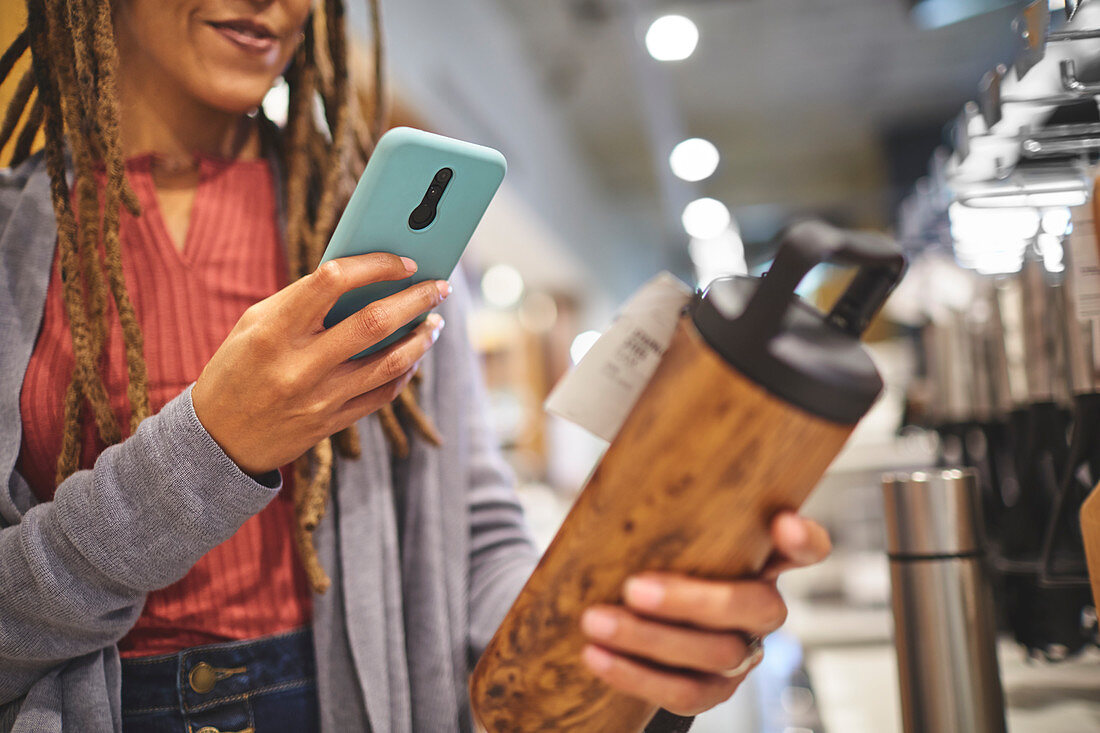 Woman photographing insulated bottle in store