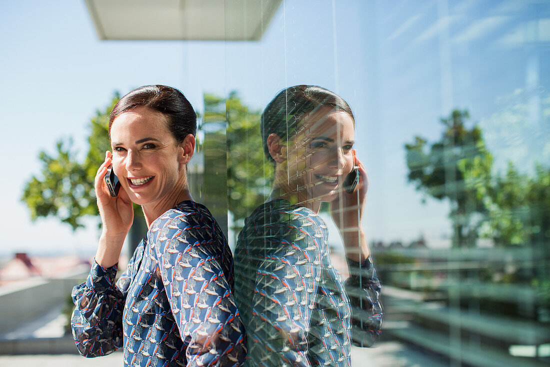 Smiling businesswoman talking on cell phone outdoors