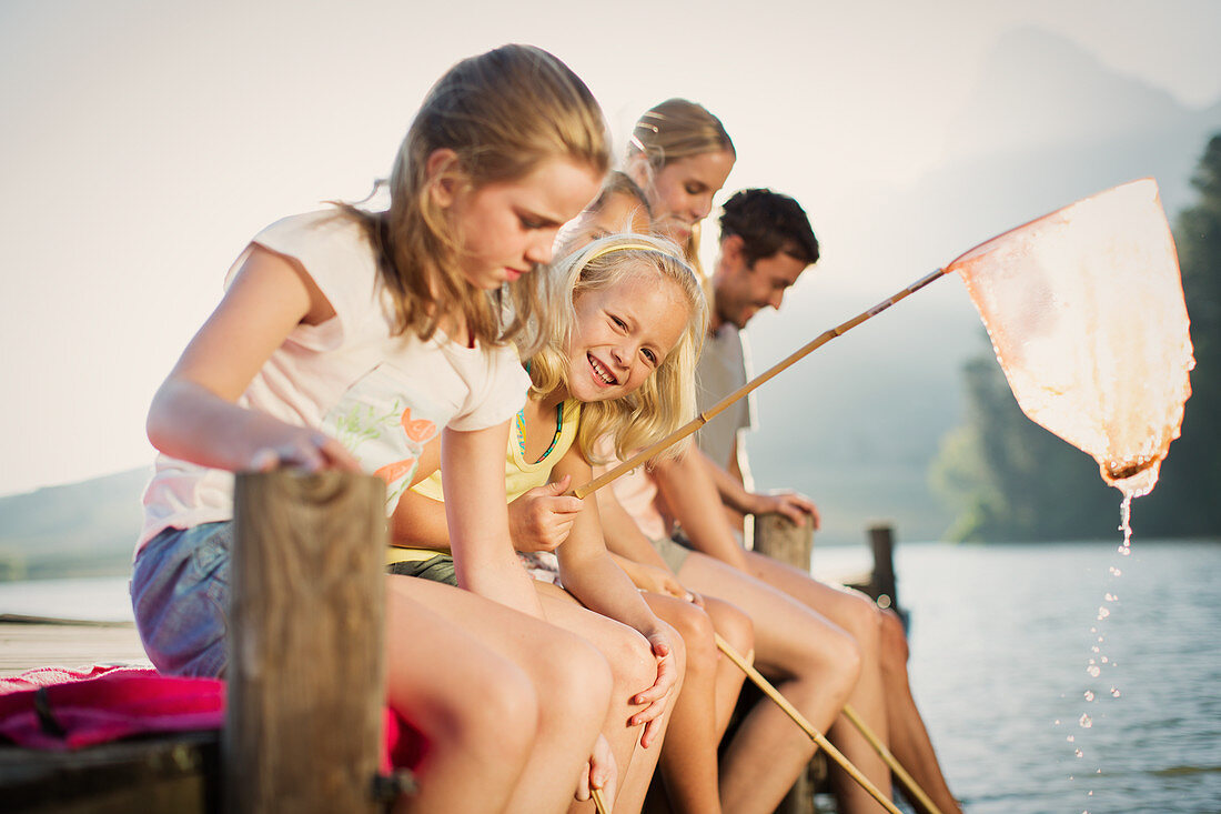 Family with fishing nets on dock over lake