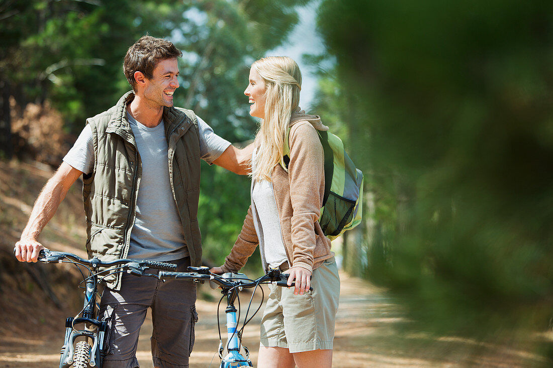 Smiling couple with mountain bikes in woods
